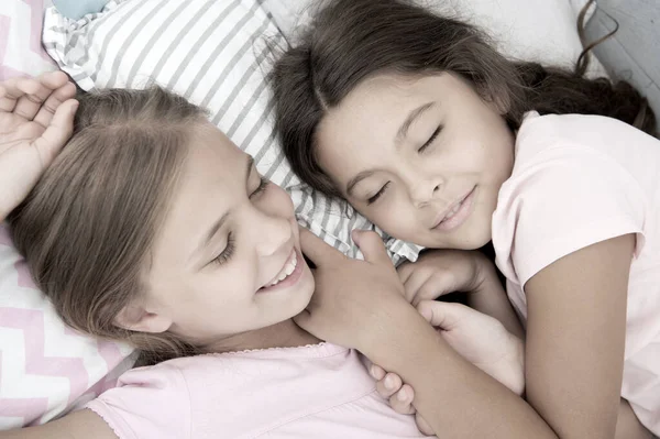 Pleasant dream on her mind. Girls fall asleep after pajamas party in bedroom. Girls have healthy sleep. Children relax on bed. Sleepy kids in pajamas having rest on comfortable bed. Happy childhood — Stock Photo, Image