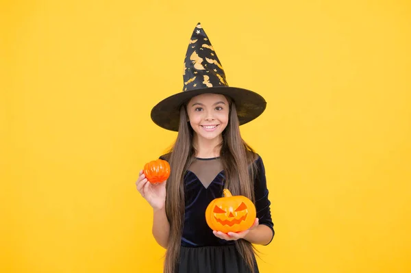 Bambino col cappello da strega. Il bambino tiene la zucca spaventosa. stregoneria e incantesimo. vacanza autunnale infanzia. mago donna. teen girl pronto a festeggiare. festa in costume divertente. Jack o lanterna. felice Halloween — Foto Stock