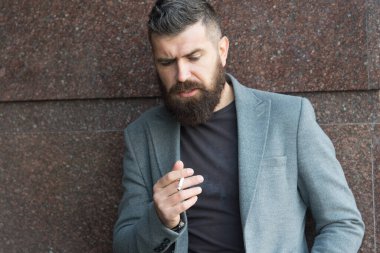 Kendi tarzında. Karizmatik iş adamı dışarıda sigara içiyor. Sakallı adam sigara içiyor. Ceketli vahşi, olgun bir hippi. Erkek, sakallı, bakımlı. Tarz sahibi bir adam. sigara bağımlılığı