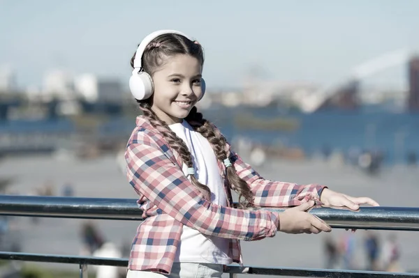 Haga feliz a su hijo con los auriculares para niños mejor calificados disponibles en este momento. Niña escuchar música al aire libre con auriculares modernos. Auriculares para niños probados y clasificados mejor a peor. Disfruta del sonido — Foto de Stock