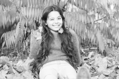 Güzel mevsim. Güneşli bir hafta sonu. Parkta güneşli bir günde dinlenen bir kız. Sonbahar sıcağı. Sonbahar parkındaki zarif, güler yüzlü kız. Düşen yapraklar. Sonbahar doğası. Küçük mutlu çocuk yapraklarla oynuyor.