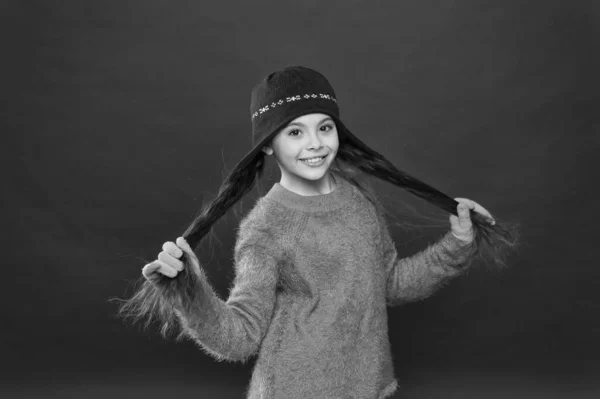 Pelo envidiablemente largo solo sucede. Chica feliz mantenga largas cerraduras fondo rojo. Niño pequeño sonríe con el pelo largo morena. Cortando cabellos gruesos y largos. Rutina de cuidado del cabello para invierno —  Fotos de Stock