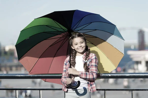 Маленька красива дівчинка, що стоїть з барвистою парасолькою. Дівчина на мосту. Ховається від сонця з парасолькою. Яскраві відтінки дівчини щасливий настрій. Очікування дощу під парасолькою — стокове фото