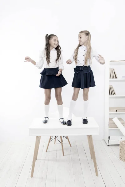 No topo. Meninas populares na sala de aula. Amizade escolar. Estudantes arrumado uniforme da escola aparência. Felicidade infantil. Dia da escola. Crianças estudantes da escola bonito ficar na mesa. Na mesma onda — Fotografia de Stock