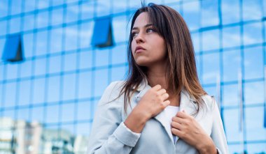 Başka tarafa bakıyor. Şık giyinmiş güzel bir bayan. Kadın güzelliği ve moda. Patron iş kadını. İş iletişimi. Zarif takım elbiseli kendine güvenen bir kadın. Kentsel arka planda bir kız