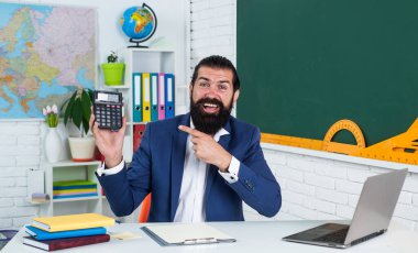 Mutlu erkek, sakallı, matematik ve matematik dersinde hesap makinesiyle hesap yapıyor.
