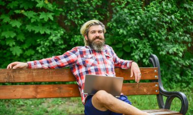 Çalış ve rahatla. İnternette çalışıyorum. Hippi parkta ilham kaynağı oldu. Modern laptop. Uzaktan kumanda. Temiz hava. Gezici internet. İnternetten alışveriş. Çevik iş. Sakallı adam yedek kulübesinde oturuyor.