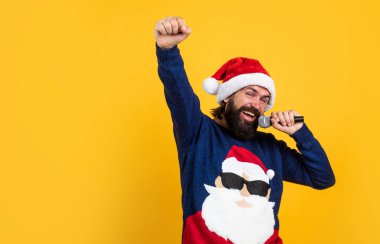 Pozitif ol. Xmas alışveriş zamanı. Hediyeler ve hediyeler hazırla. Karaoke. Noel Baba şapkalı mutlu sakallı adam mikrofonda şarkı söylüyor. Yeni yıl partisi. Kış tatilini kutlamak. Noel şarkıları