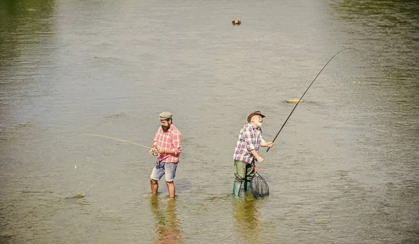 Muy largo. padre e hijo pescando. aventuras. Pesca de caza mayor. amistad masculina. dos pescador feliz con caña de pescar y red. recreación y ocio al aire libre. pasatiempo y actividad deportiva. Cebo de trucha —  Fotos de Stock