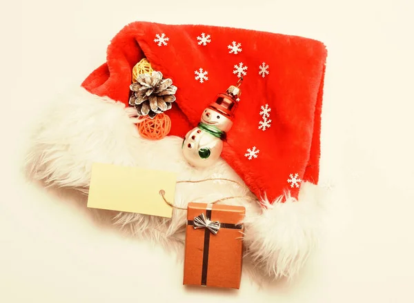 Mantenga las tradiciones familiares. Santa sombrero rojo blanco vista superior del fondo. Regalos de Navidad de Santa. Los atributos de las vacaciones de invierno. Año nuevo y la celebración de Navidad. Sombrero de Santa con caja de regalo de Navidad — Foto de Stock