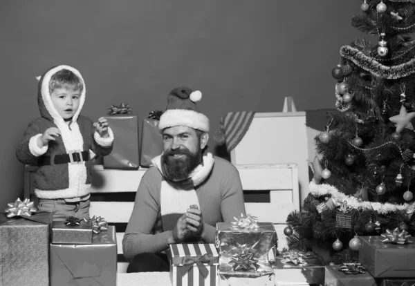 Santa and little assistant among gift boxes near Christmas tree. — Stock Photo, Image