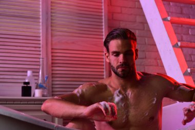 Tuvalet eşyaları ve merdivenlerle banyoda meditasyon yapan adam.