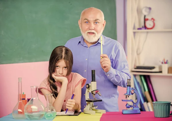 Descubriendo la cura. aula de ciencias. niña pequeña con el hombre tutor estudiar química. Microscopía. Equipo de laboratorio. utilizar lupa. profesor maduro de biología. Niña en el laboratorio escolar — Foto de Stock