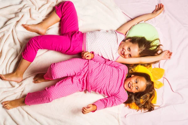 A mosolygó arcú gyerekek rózsaszín háttéren fekszenek — Stock Fotó
