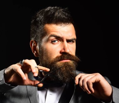 Sakallı adam çelik makas tutuyor. Takım elbiseli maço.