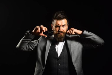 Maço takım elbiseli, bıyıklı ve sakallı.