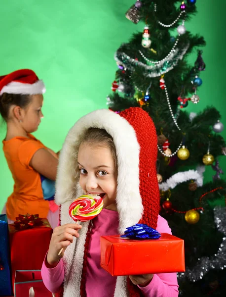 Kid in Santa Claus kostuum met geschenkdozen en lolly — Stockfoto