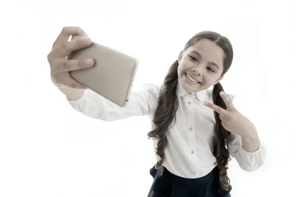Glad flicka tar selfie isolerad på vitt. Barn leende med seger hand gest på smartphone. Digital marknadsföring i den virtuella världen. Selfiekul. Söt bloggare gör videosamtal. Modernt liv och teknik — Stockfoto