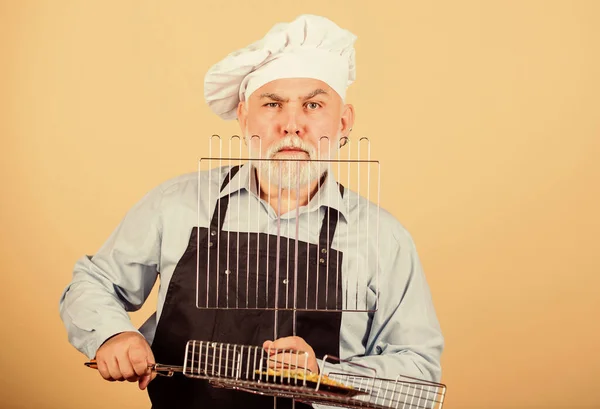 Hij geeft de voorkeur aan grillvoedsel. Picknick en barbecue. Keukenregels. Maak het eten klaar voor familie. Familieweekend. Oudere man met koksmutsen. Kook mannen met een baard. kookgerei voor de barbecue — Stockfoto