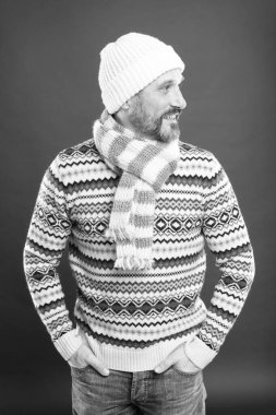 Serin mevsim için modaya uygun kıyafetler. Şık kış tarzı kırmızı arka planda mutlu bir adam. Modaya uygun örgü şapkalı olgun adam gülüşü. Soğuk hava için modaya uygun ve sıcak şeyler.