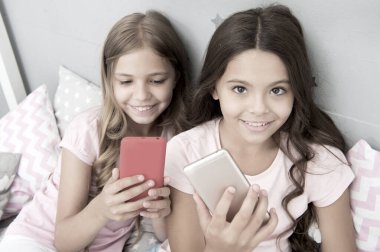 Pijama partisi konsepti. Kız kıza mutlu bir çocukluk. Akıllı telefonlu uzun saçlı kızlar modern teknoloji kullanır. Hadi selfie çekelim. Arkadaşlarının sosyal ağındaki fotoğrafını gönder. Çocuklar yatak odasında selfie çekiyor.