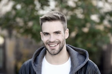 İnsanoğlu böyle görünmek ister. Sonbahar gününde mutlu bir adam. Yakışıklı adam sıradan bir şekilde gülümsüyor. Tıraşsız sakallı ve şık saç tıraşlı beyaz bir adam. Sonbahar modası. Yaşam biçimi