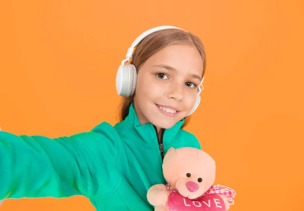Selfie time. Musical education. Musical taste. Musical accessory. Leisure and fun. Got this feeling. Girl with soft toy listening music wireless headphones. In love with stereo sound