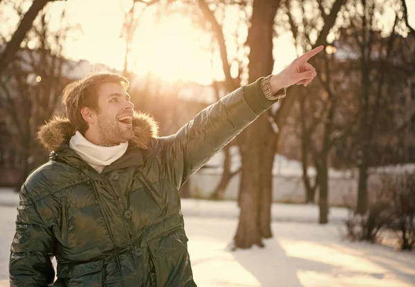 Boldog fickó zöld gömbölyű kabát. Az ember élvezi a téli tájat. A természet gyönyörű. Odanézz! A férfi ujjal mutogat. férfi bundában, prémkapucnival. melegséget és kényelmet. kedvenc évszak — Stock Fotó