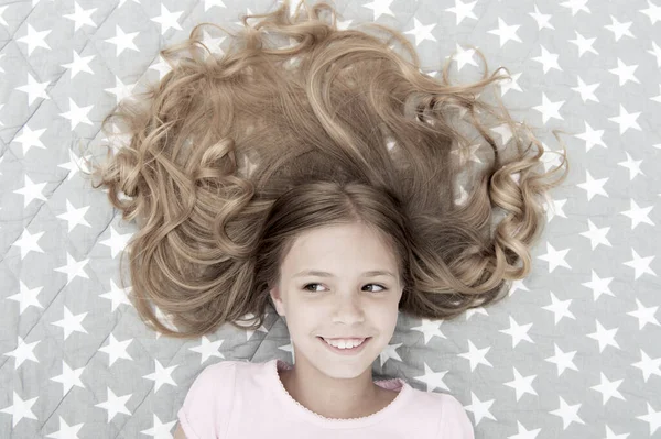 子供の巻き毛リラックス。コンディショナーマスク有機オイルは、髪の光沢と健康を維持します。素晴らしい髪のヒント。翌朝でさえも巻き毛を保つ。女の子子供とともに長いです毛レイ上のベッドトップビュー — ストック写真