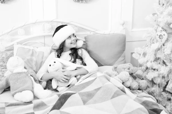 Magiczny poranek. Słodki dom. Dziewczynka małe dziecko relaks na łóżku lekkie wnętrze z dekoracjami świątecznymi. Przytulny pokój. Małe dziecko relaksujące się w sypialni. Dzieciak leżał w łóżku relaksując się. Koncepcja Wigilii — Zdjęcie stockowe