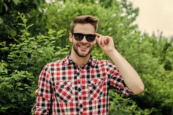 Homme parfait. jeune homme non rasé. homme sexy portant des vêtements à carreaux posant dans le parc. Bon jeune homme confiant debout et souriant en chemise urbaine. style de mode denim. bel homme à la barbe — Photo