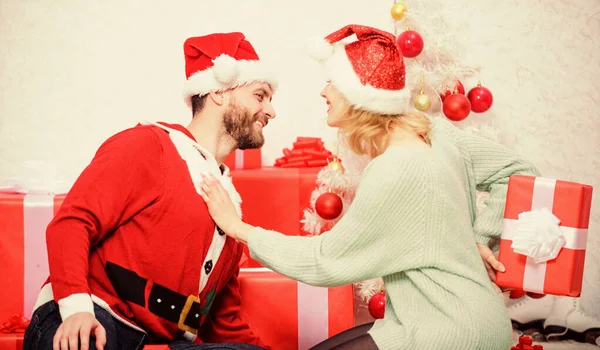 Birbirine aşık çiftler Noel tatilinin tadını çıkarıyorlar. Aile Noel sürprizi hazırladı. Noel hediyesini açıyorum. Sevgi dolu çift, hediye paketini açarken gülümsüyor. — Stok fotoğraf