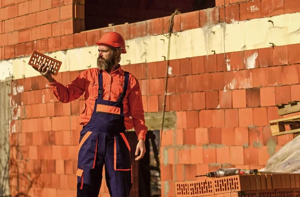 Brick building material used to make walls. Lightweight brick made from expanded clay aggregate. Element in masonry construction. Builder hold brick. Bearded man wear hard hat at construction site — Stock Image Brick building material used to make walls. Lightweight brick made from expanded clay aggregate. Element in masonry construction. Builder hold brick. Bearded man wear hard hat at construction site Royalty Free Stock Photos