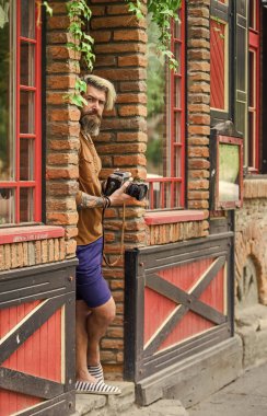 Açık havada fotoğraf çekimi. Geçmişe dönük kamerası olan vahşi bir gezgin. Modern hayatta fotoğrafçılık. Seyahat ipuçları. Profesyonel fotoğrafçı klasik kamera kullanır. Sakallı hippi adam fotoğraf çek.