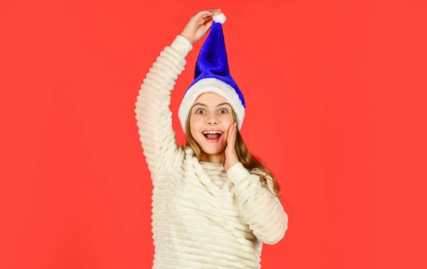 Menina adorável usar Papai Noel chapéu fundo vermelho. Expressão facial emocional. Feliz infância. A contar dias até ao Natal. Festa de Natal. Não pode conter as emoções. Convite de Natal — Fotografia de Stock