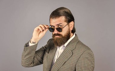 Mükemmel sakallı ve bıyıklı acımasız bir iş adamı. Ceketli gerçek patron. Olgun adam gözlük takıyor. Güven ve karizma. Yakışıklı adam ofis kıyafeti giyer. Erkek güzellik ve moda. Seni baştan çıkarmak.