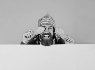 Sıcak şapkalı adam gözlerini kiraz yapraklarıyla kapatıyor.