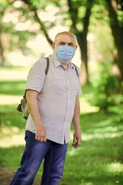 Let op de voorzorgsmaatregelen tijdens de pandemie. gezond leven. Draag een masker in het park. zorg voor je gezondheid. Bescherm jezelf tegen virussen. Een man met een beschermend masker. lopen buiten op coronavirus quarantaine. Kijk daar eens. — Stockfoto