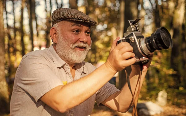 Look at this. Happy pensioner hold camera in nature. professional photographer with camera. The photographer hold DSLR camera. makes beautiful pictures on film retro camera. freedom man traveler — Stock Photo, Image