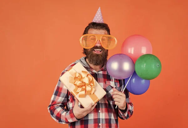 Ετοιμάσου για την επέτειο. διαχειριστής εκδήλωση με κουτί δώρου. βάναυσος άντρας στο πάρτι. Αστείος άντρας με καπέλο γενεθλίων. Χαρούμενες γιορτές. Το πάρτι τρελαίνεται. διασκεδάζοντας με μπαλόνια — Φωτογραφία Αρχείου