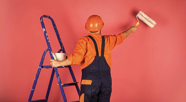 Isolamento térmico funciona. Escadaria do pintor. Para fazer reparações. homem na parede de pintura de roupas de trabalho em quarto vazio. pintor em geral e tampa com balde de tinta. construtor trabalhador pintura fachada — Fotografia de Stock