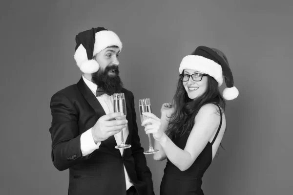 Vánoce se blíží. Vánoční večírek. formální zamilovaný pár slaví nový rok. Muž ve smokingu se ženou v Santově klobouku. Veselé Vánoce a veselé Vánoce všem. obchodní muž a dívka pít šampaňské — Stock fotografie