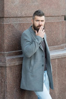 Sakallı, sigara içen olgun bir hippi. Bağımlılık. Bıyıklı, vahşi, beyaz bir hippi. Erkek kötü alışkanlıkları. Modern hayatta gündelik moda. Kendine güvenen ve yakışıklı vahşi bir adam. duman