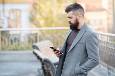 SMS pazarlaması yapan kişilere ulaş. Sakallı adam açık havada SMS okudu. Kısa mesaj atıyorum. Mobil cihaz. Yeni teknoloji. Modern hayat. İş iletişimi