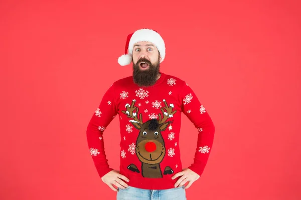 Surprised bearded man wearing funny knitted sweater and santa claus hat for celebrating new year holiday, happy new year — Stock Photo, Image
