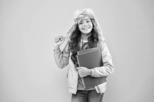 Ayudarte a estudiar. niño ropa de abrigo fondo rosa. la vida diaria de los alumnos. colegiala llevar mochila y libros. No más exámenes. pequeña chica feliz sombrero de oreja. de vuelta a la escuela. vacaciones de invierno y vacaciones —  Fotos de Stock