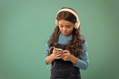 E-postaya cevap ver. Küçük çocuk akıllı telefondan çalma listesi yapıyor. Küçük kız mp3 çalar kullanıyor. Modern hayatta okumak. Kız dijital cihaz kullanıyor. Çocuklar için sıradan moda. Uzun saçlı çocuk kulaklıkla müzik dinliyor.