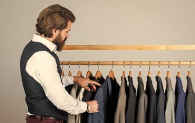 Hangi tasarım daha iyi. İş adamı. Kendine güvenen terzi erkek ceketi tasarlıyor. Mezura takan yakışıklı bir sartor. Erkek güzellik ve moda. Sakallı adam, terzi kıyafetleri. resmi ve ofis dolabı