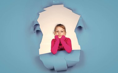 Kadın kuaför salonu. Güzellik ve moda. Mutlu çocuğun sıradan bir görünüşü var. Modayı takip eden çocuğun mutlu bir çocukluğu var. Mavi arka planda küçük bir kız. Neşeli duyguları olan çocuk.