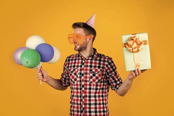 Riktig snattare. Killen håller festliga ballonger. Glad högtid firande. Dags för skoj och presenter. Grattis på födelsedagen eller årsdagen. Känn glädje och glädje. En riktig festprisse. rolig man i födelsedagshatt — Stockfoto